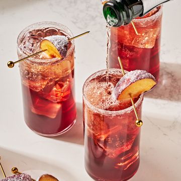 a refreshing holiday cocktail with plum wine, prosecco, maraschino cherry syrup, lemon, and bitters, garnished with a sugared plum