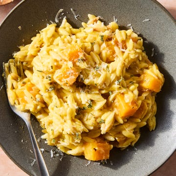 creamy butternut squash orzo on a plate topped with cheese and herbs