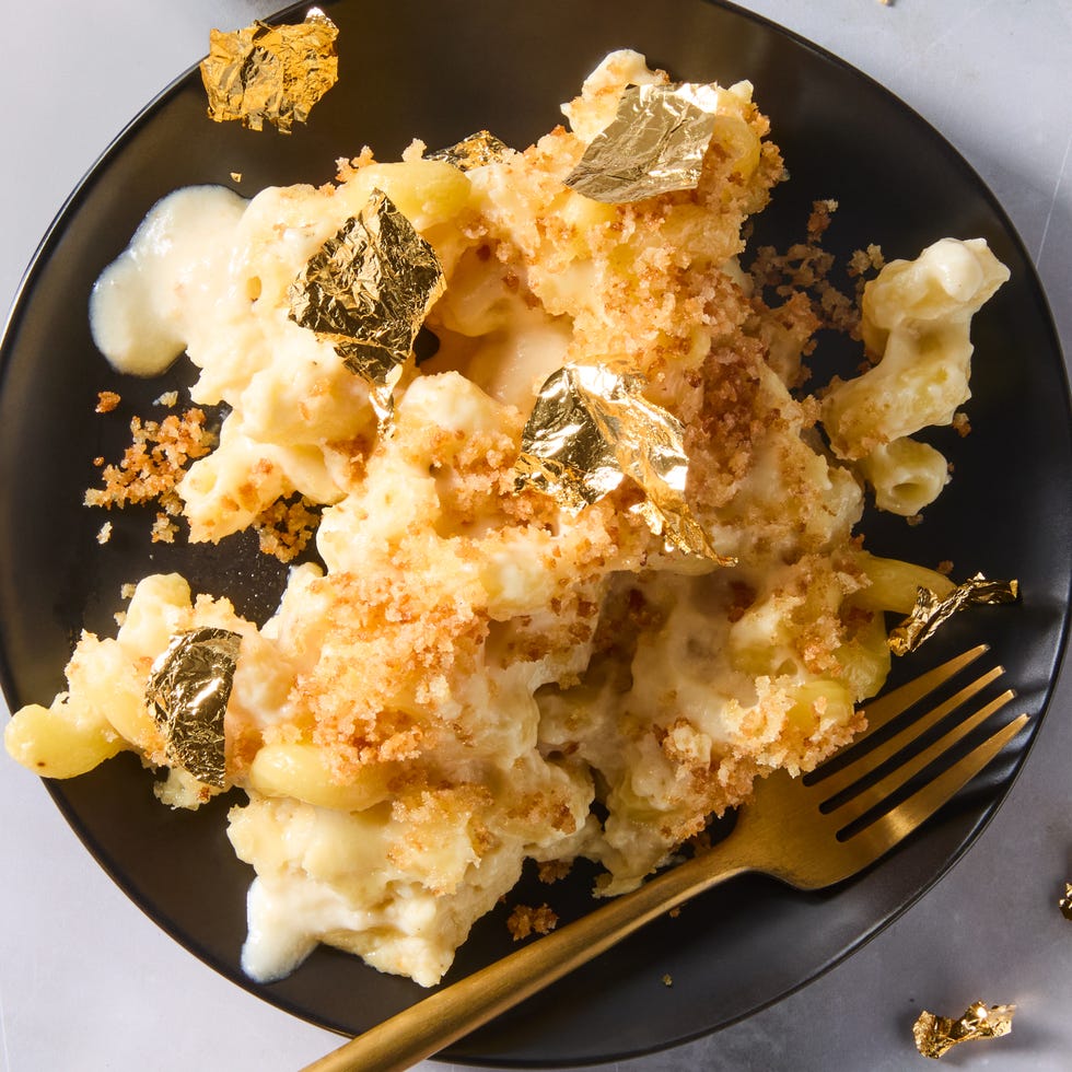 million dollar mac and cheese topped with panko and gold leaf on a plate with a fork