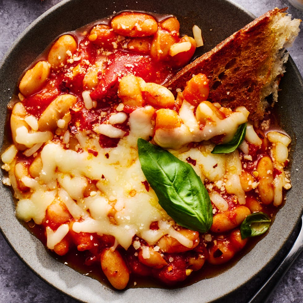 pizza beans topped with mozzarella and parmesan and basil in a bowl with a piece of toast