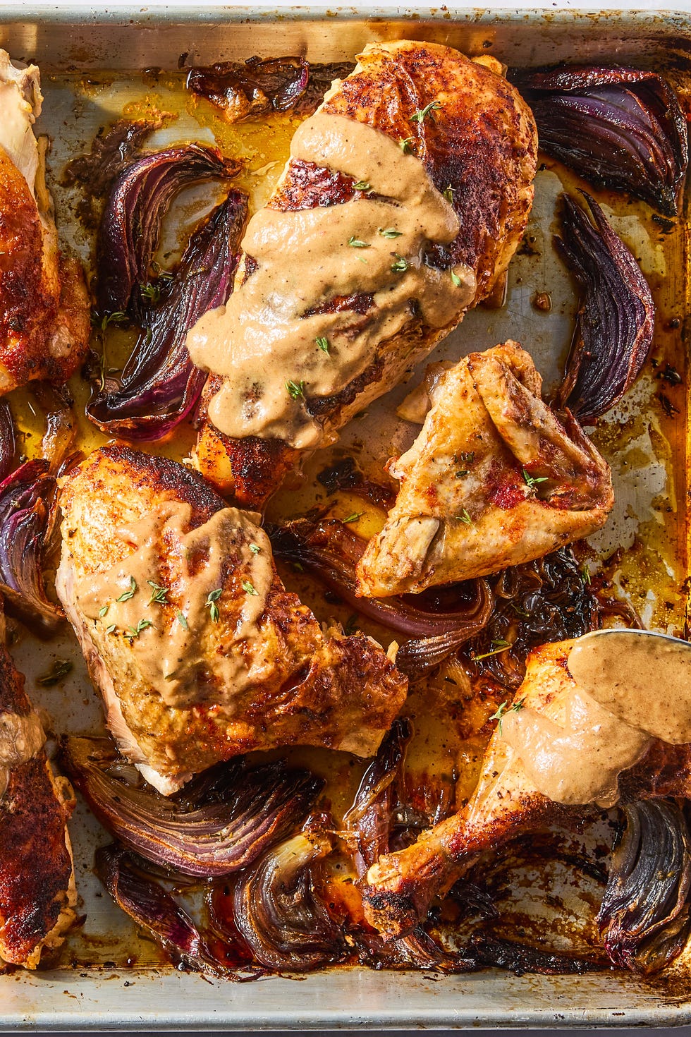 Sheet Pan Roasted Red Onion Chicken paprika dusted chicken roasted on a bed of herby sliced red onions and whole garlic cloves then topped with an umami rich, spoonable sauce made from chicken fat roasted, charred onions, butter, sweet white vinegar, and crushed red pepper