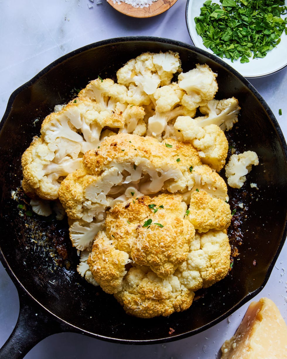 whole roasted cauliflower sliced up in a cast iron skillet