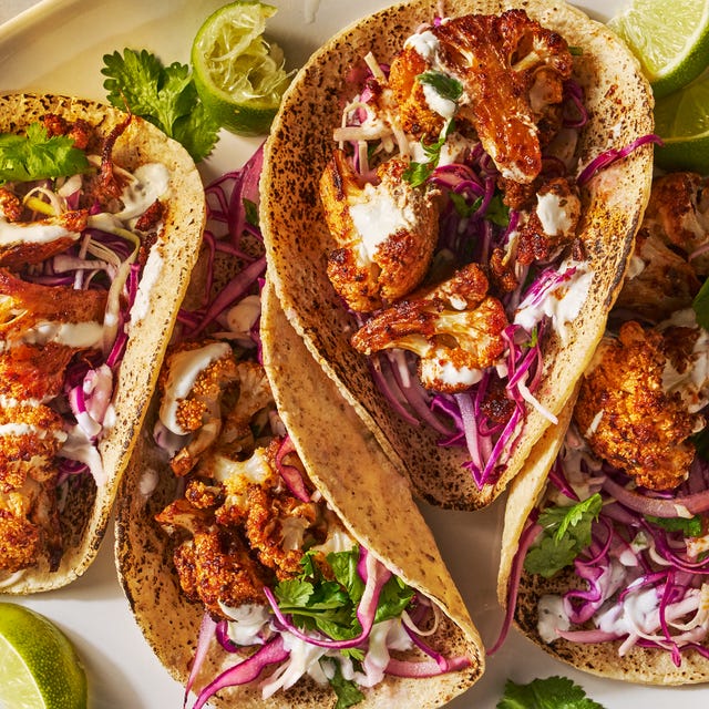 cauliflower tacos on a platter with cabbage, cilantro, and lime wedges