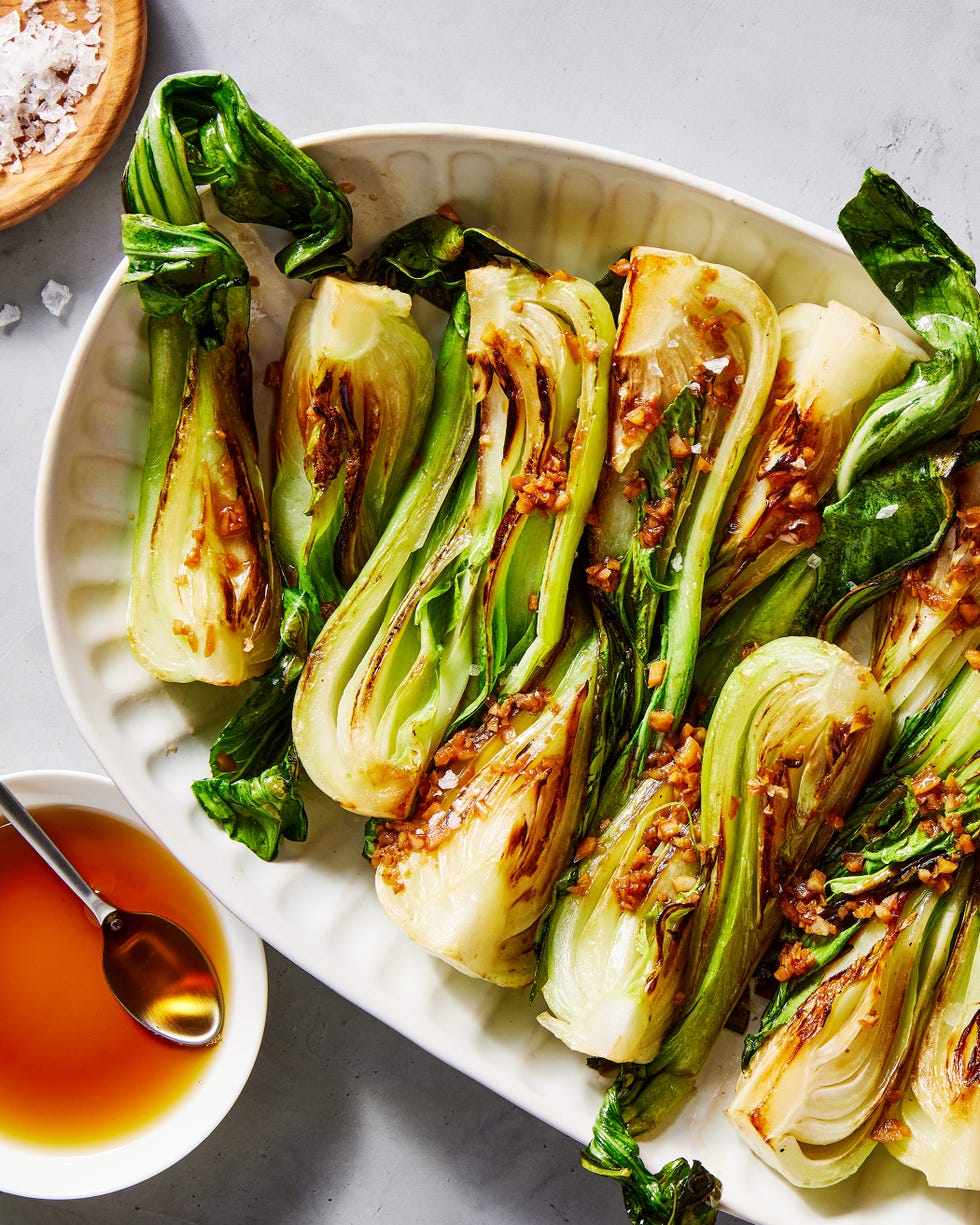 bok choy on a white platter topped with chopped ginger and garlic
