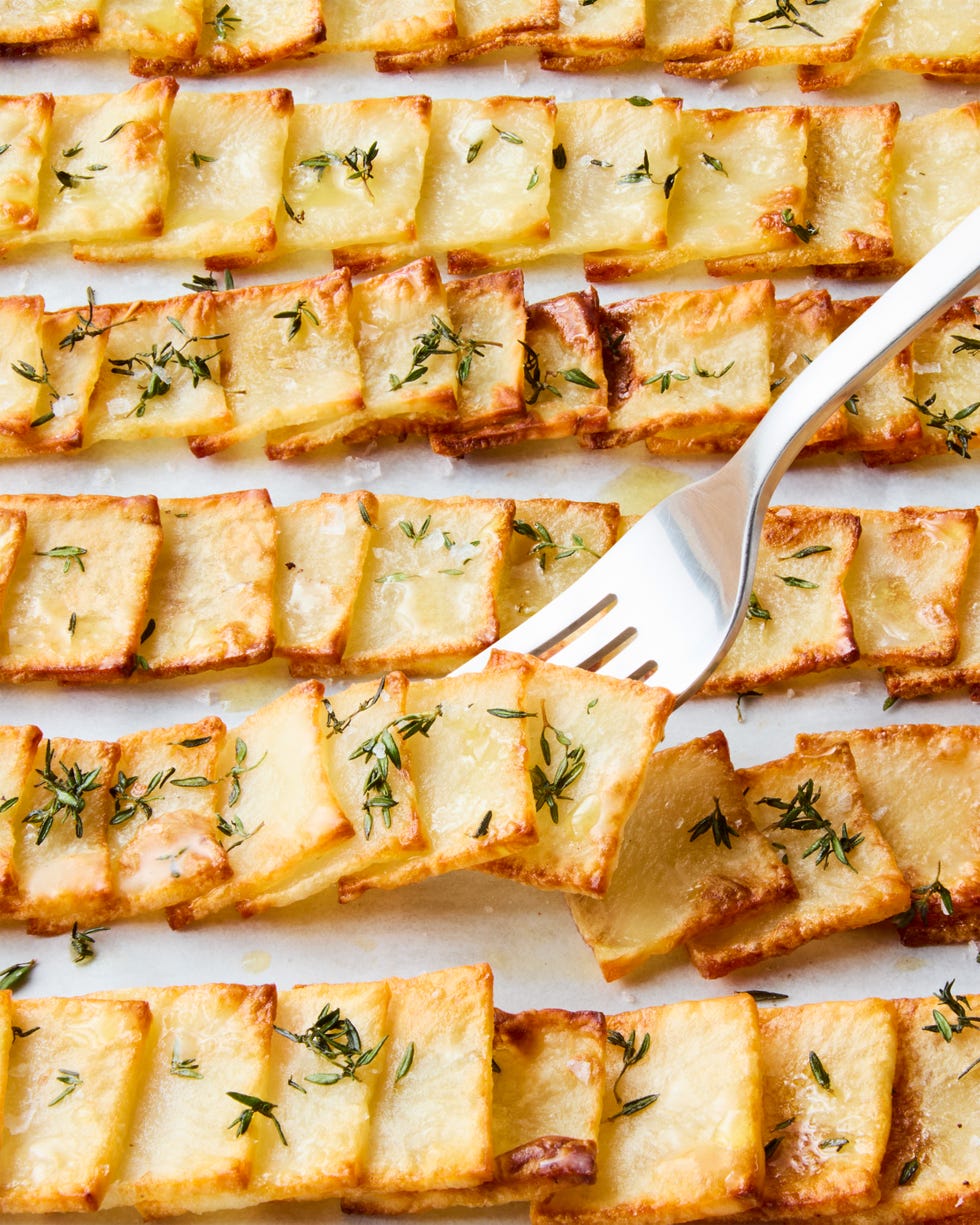 crispy domino potatoes in rows topped with thyme and flaky salt with a fork