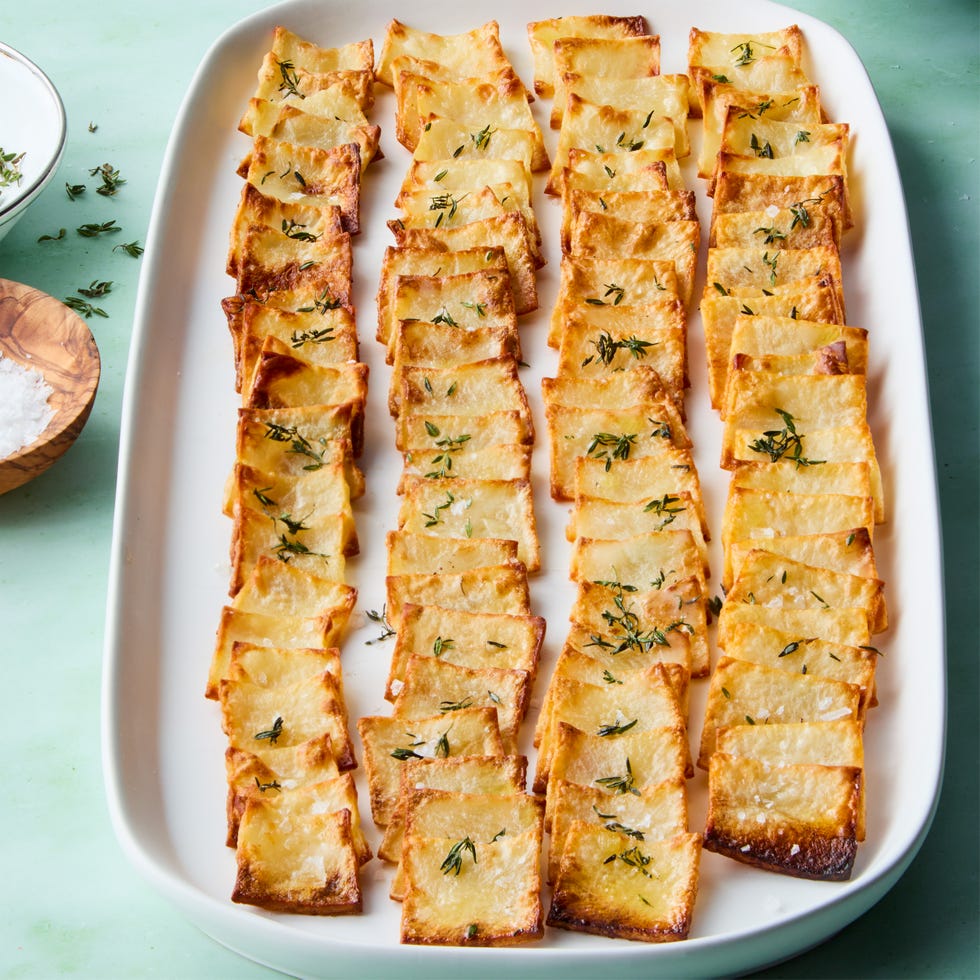 crispy domino potatoes on a white platter topped with thyme and flaky salt