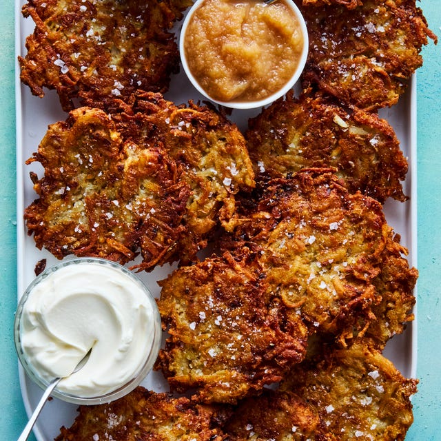 crispy latkes on a platter with bowls of sour cream and apple sauce