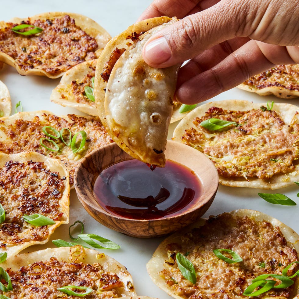 smash dumplings on a surface with a smash dumpling being dipped into a bowl of soy sauce