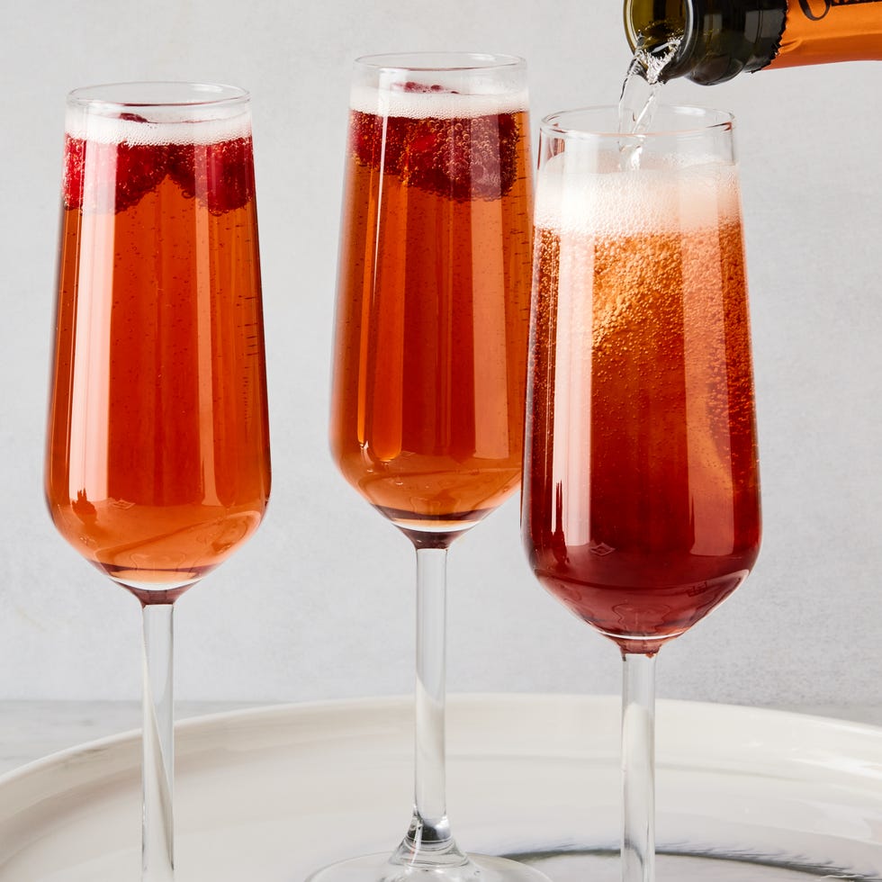 three glass flutes filled with champagne, cassis liqueur, and fresh raspberries