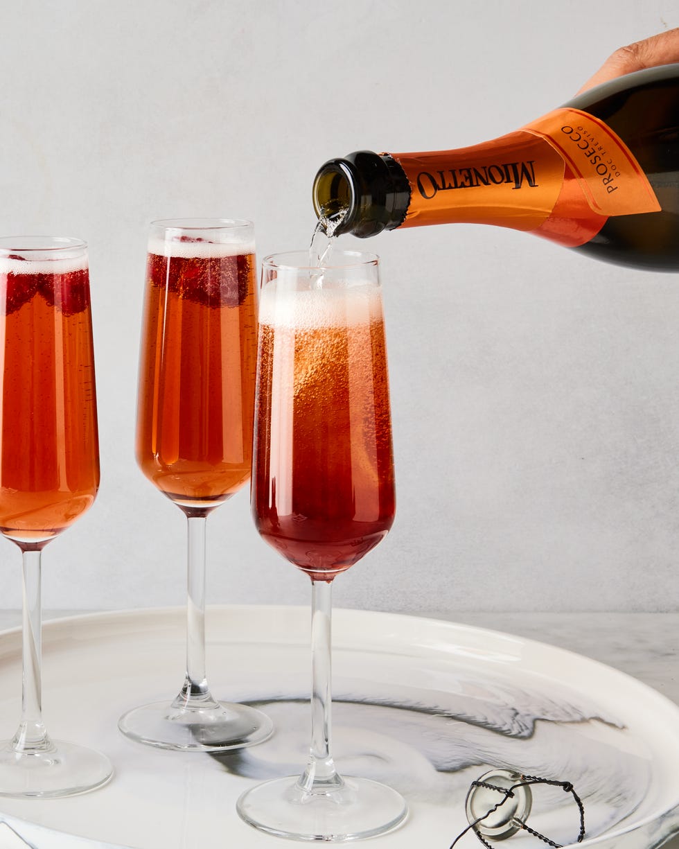three glass flutes filled with champagne, cassis liqueur, and fresh raspberries