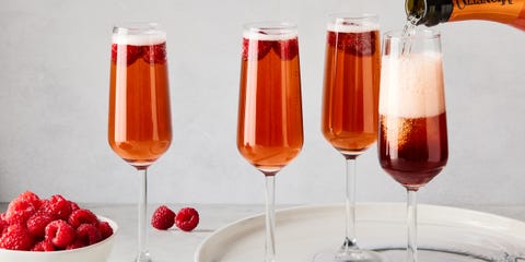 three glass flutes filled with champagne, cassis liqueur, and fresh raspberries