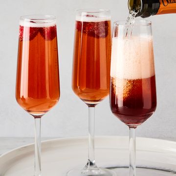 three glass flutes filled with champagne, cassis liqueur, and fresh raspberries