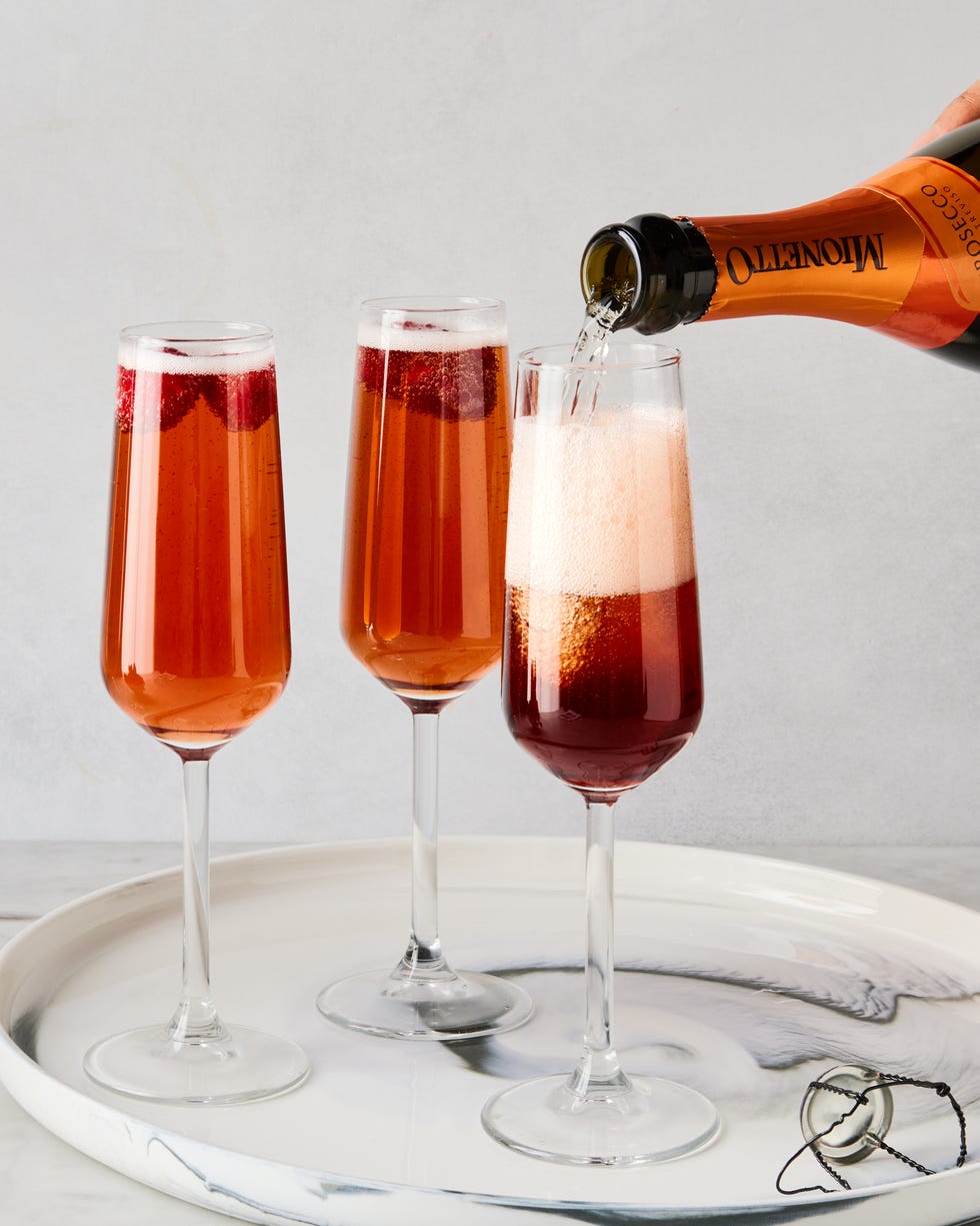 three glass flutes filled with champagne, cassis liqueur, and fresh raspberries