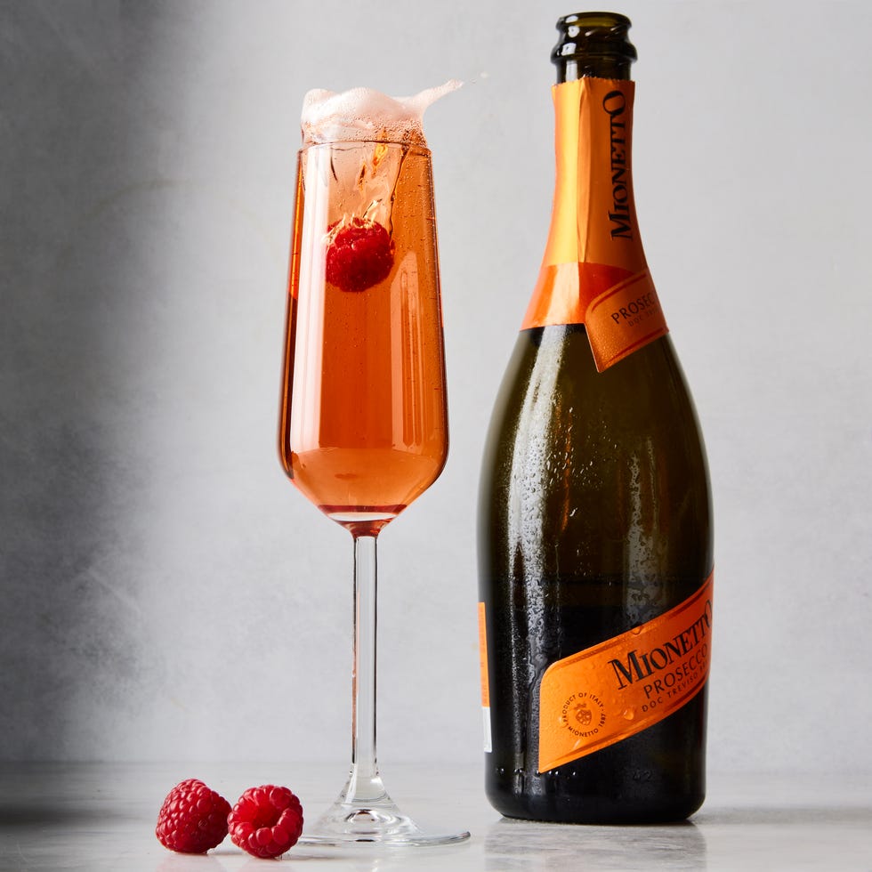 three glass flutes filled with champagne, cassis liqueur, and fresh raspberries