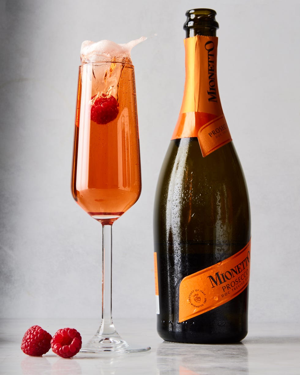 three glass flutes filled with champagne, cassis liqueur, and fresh raspberries
