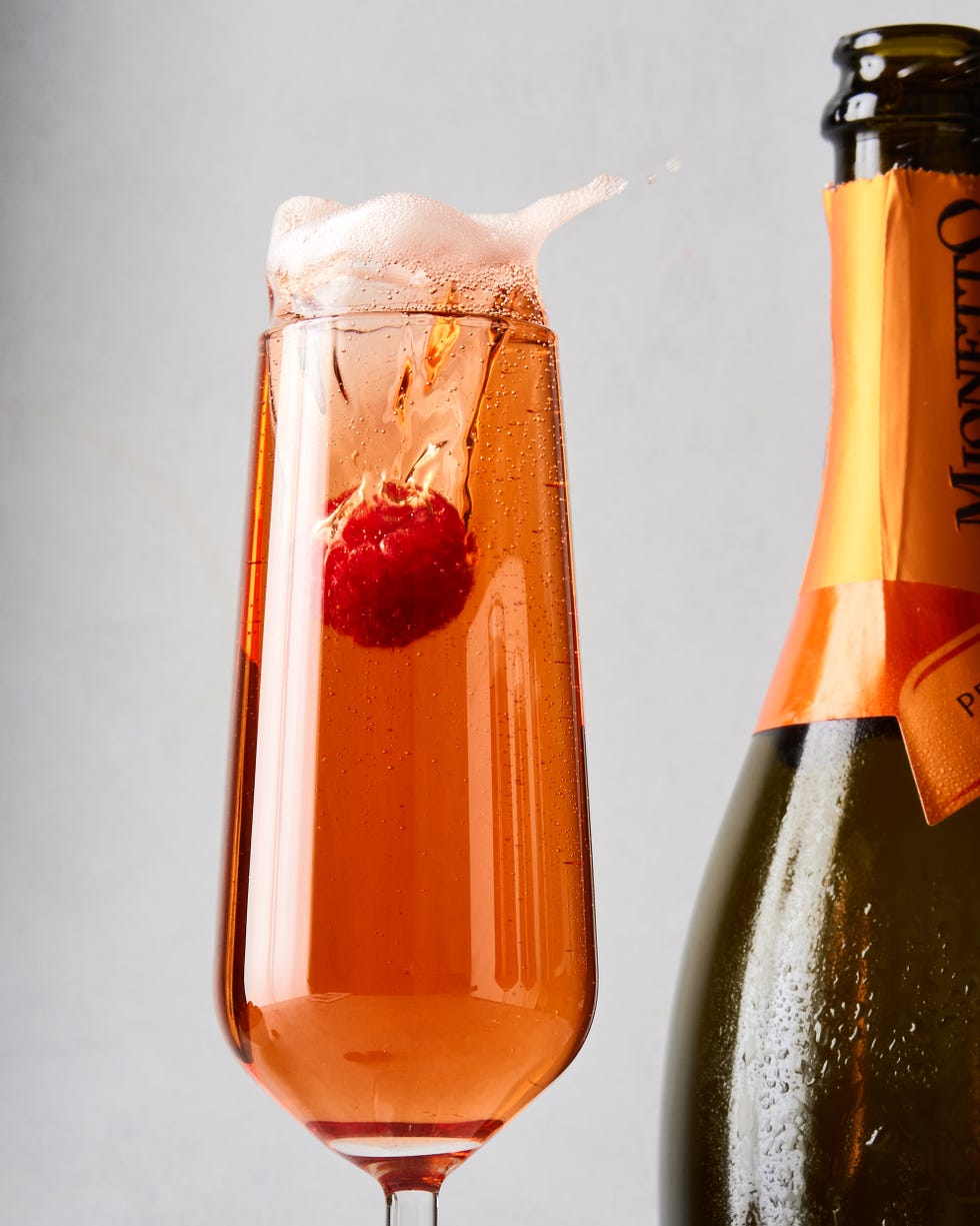 three glass flutes filled with champagne, cassis liqueur, and fresh raspberries