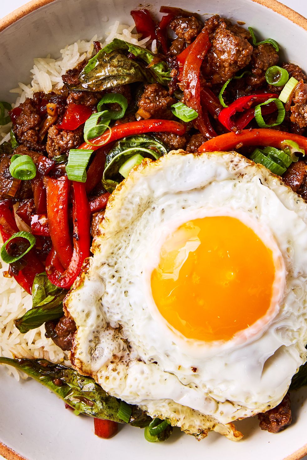 saucy, spicy, and slightly sweet ground beef tossed with peppers, fresh basil, garlic, and ginger served over white rice and topped with a runny fried egg