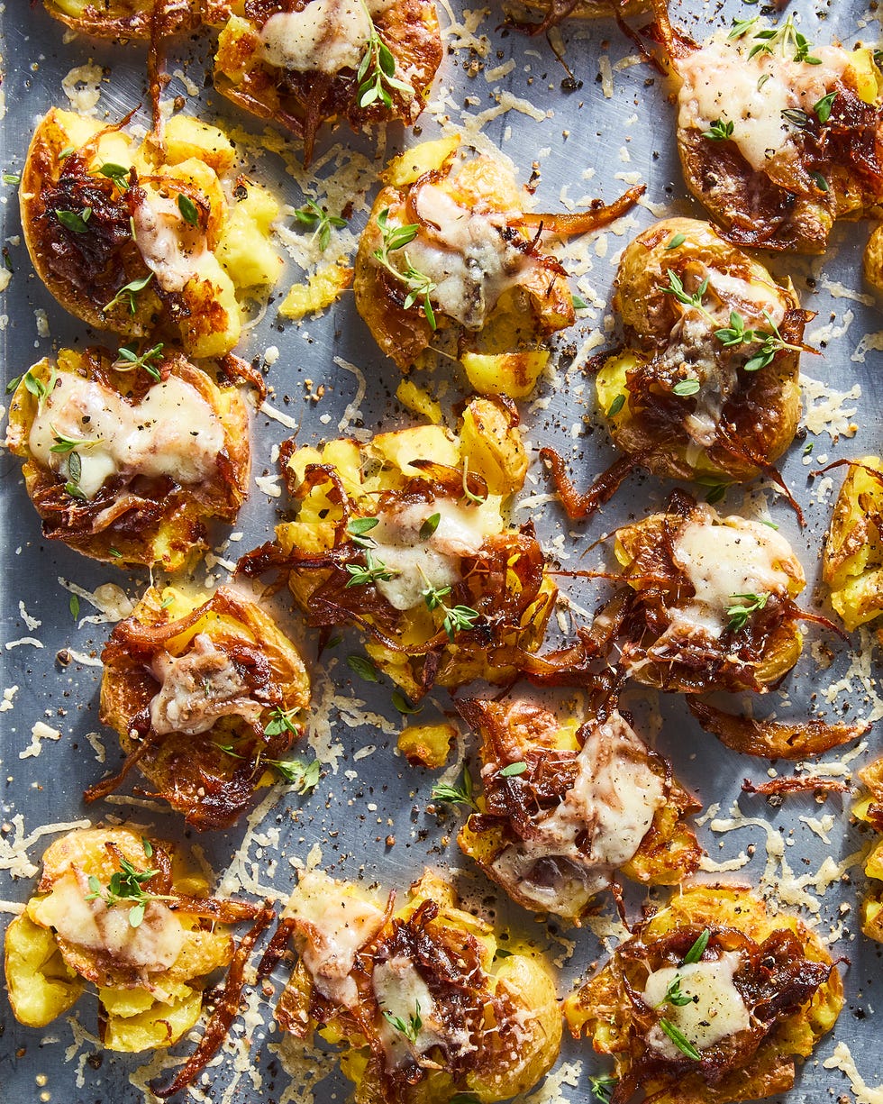 french onion smashed potatoes topped with caramelized onion, gruyere, and thyme on a baking sheet