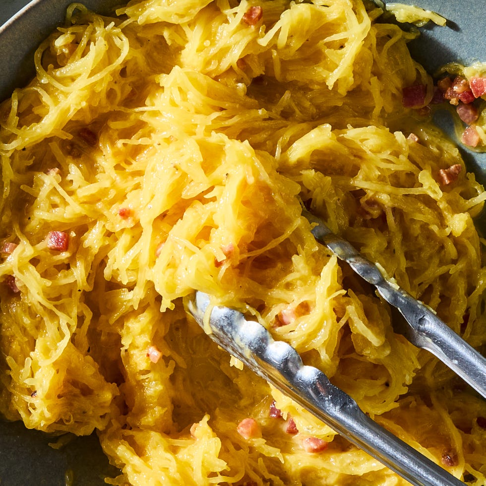 spaghetti squash carbonara in a bowl being tossed with tongs in a bowl