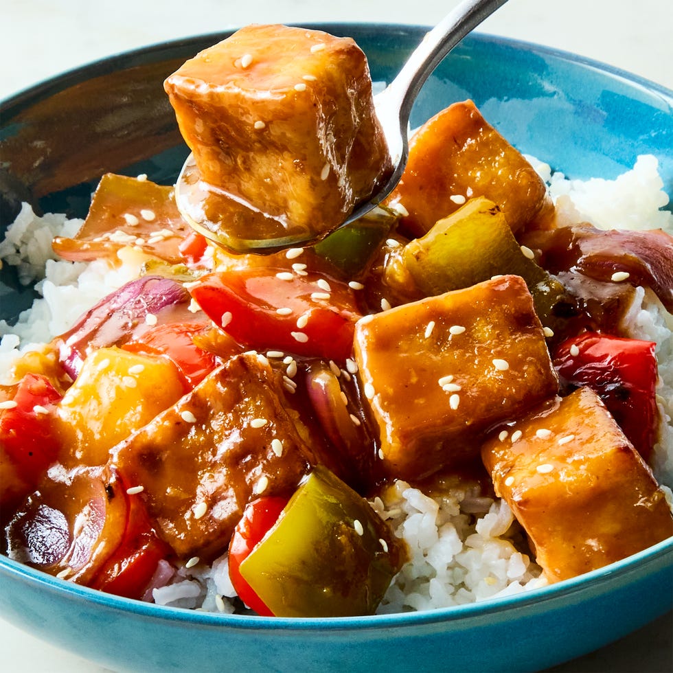 a pan of crispy tofu cubes with red onion, bell peppers, pineapple, and a sweet and sour sauce