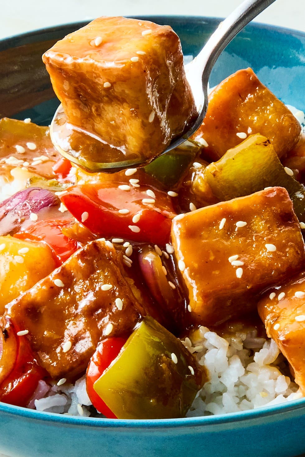Sweet and Sour tofu a pan of crispy tofu cubes with red onion, bell peppers, pineapple, and a sweet and sour sauce
