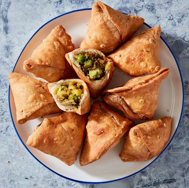 fried samosas on a white plate on a blue marble background