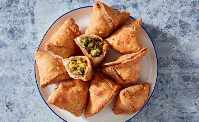 fried samosas on a white plate on a blue marble background
