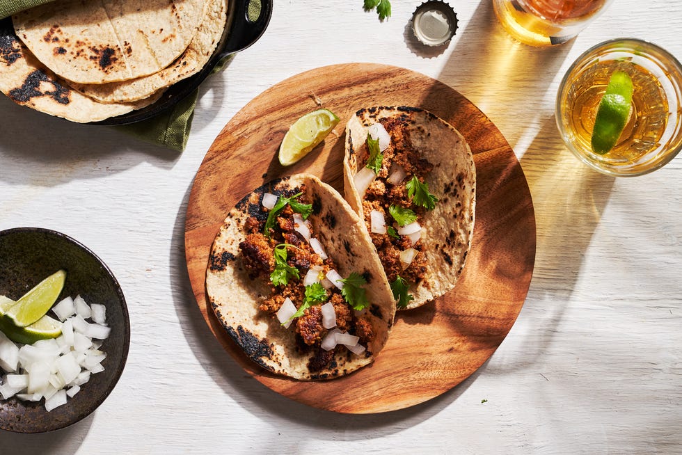 chorizo tacos, tacos with meat, onions, and cilantro, with lime wedges on the side