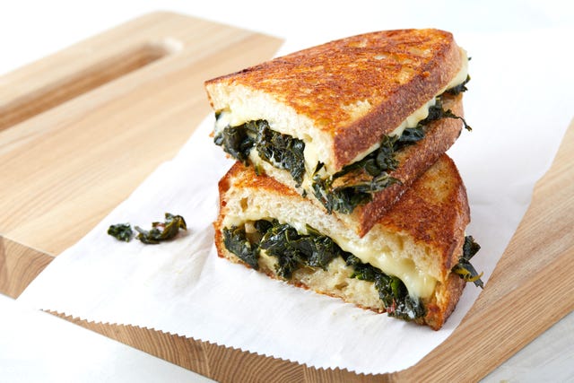grilled cheese cut in half, loaded with melty white cheese and braised kale