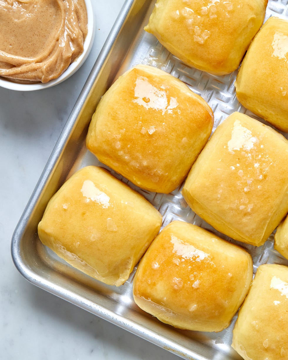 copycat texas roadhouse dinner rolls with flaky salt on a baking sheet cinnamon honey butter