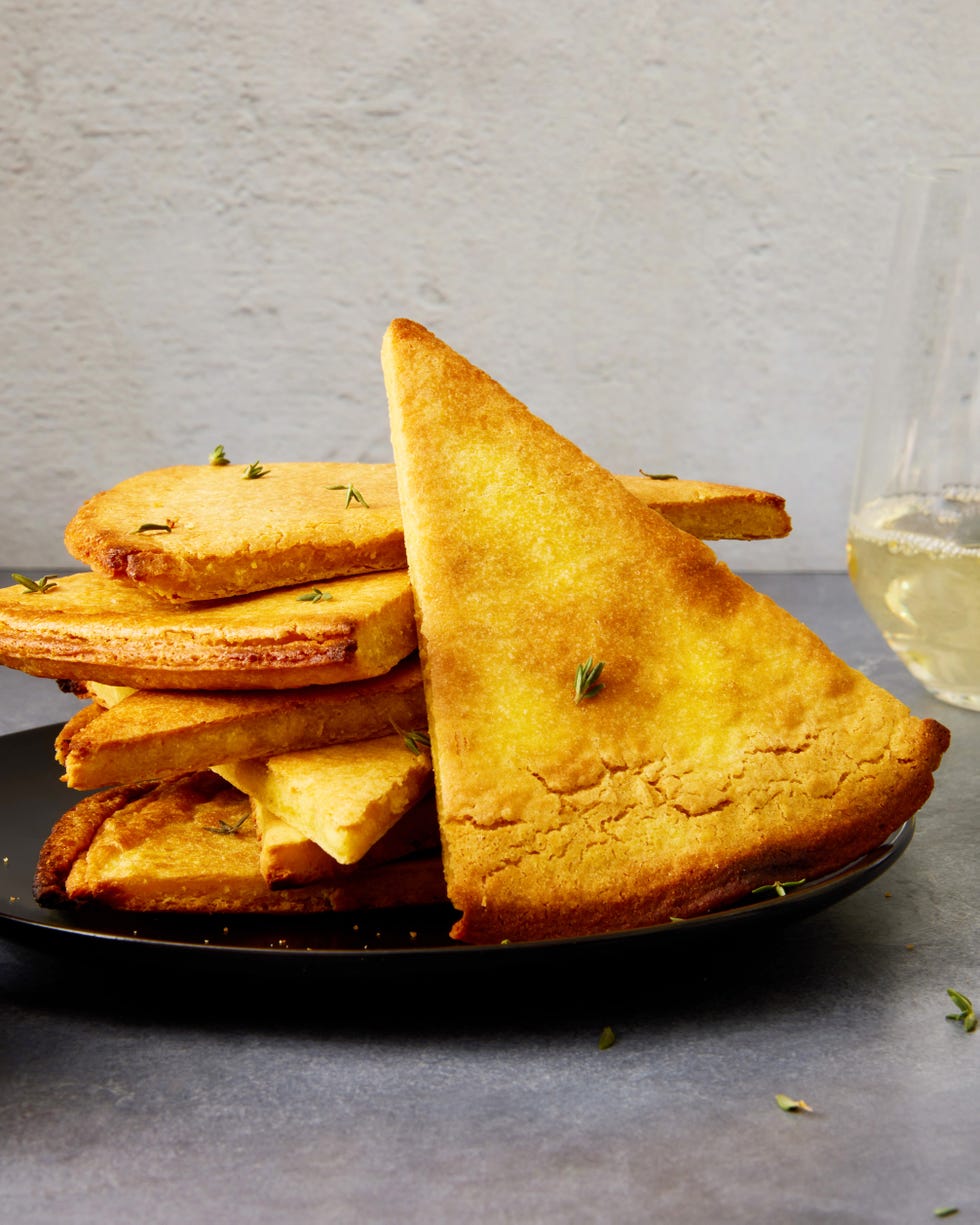 a golden brown mediterranean chickpea flatbread in a cast iron skillet with crispy edges and fresh herbs sprinkled on top