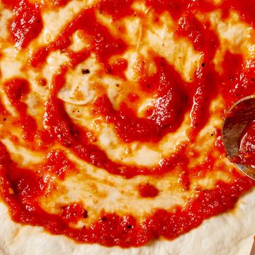 blended tomato sauce with garlic and oregano spread on unbaked pizza dough