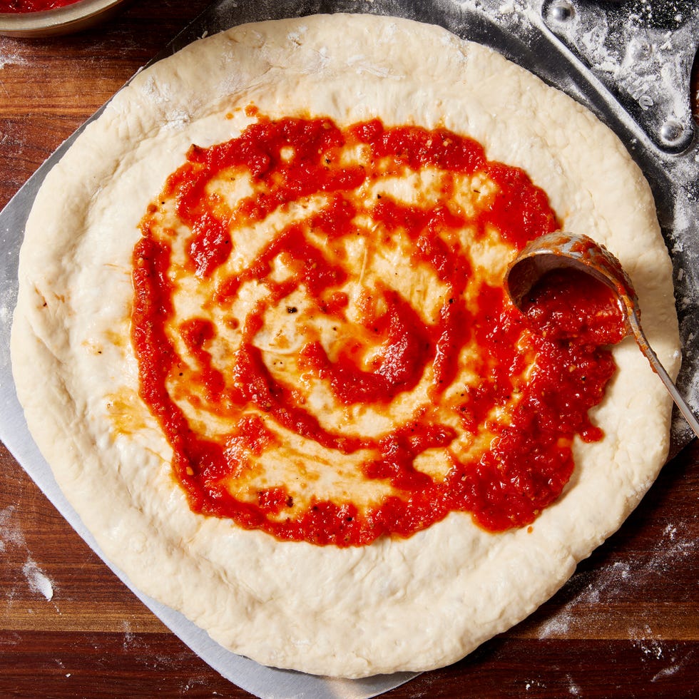 blended tomato sauce with garlic and oregano spread on unbaked pizza dough