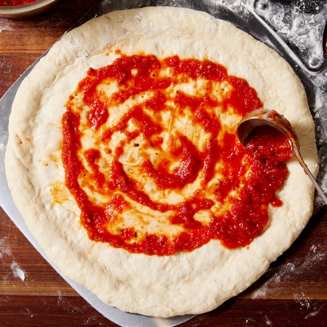 blended tomato sauce with garlic and oregano spread on unbaked pizza dough