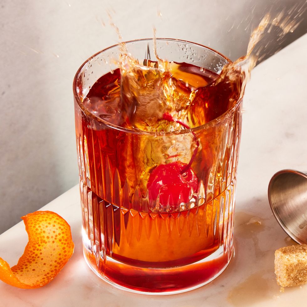 An old fashioned in a lowball glass with a large ice cube and an orange  peel