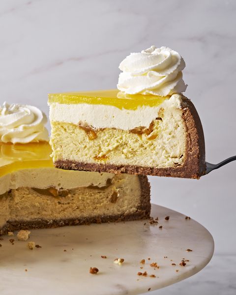 mango key lime cheesecake with vanilla coconut crust, layered with mango mousse, and mango glaze, and topped with whipped cream