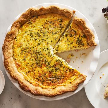ham and cheese quiche beside a plate with a slice of quiche and a salad bowl