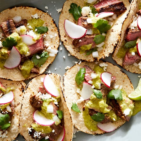 Carne Asada Tacos marinated, grilled skirt steak, piled into a corn tortilla with salsa verde, cilantro, red onion, cotija, and radish