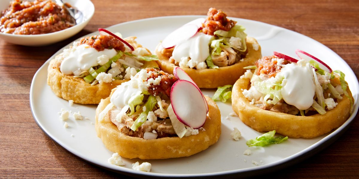 sopes made of masa harina and topped with refried beans salsa roja shredded lettuce mexican crema radishes and cojita