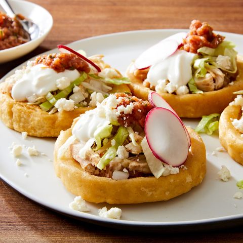 sopes made of masa harina and topped with refried beans salsa roja shredded lettuce mexican crema radishes and cojita