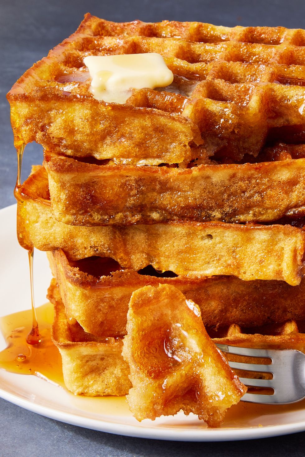 square classic waffles topped with butter and drizzled with maple syrup