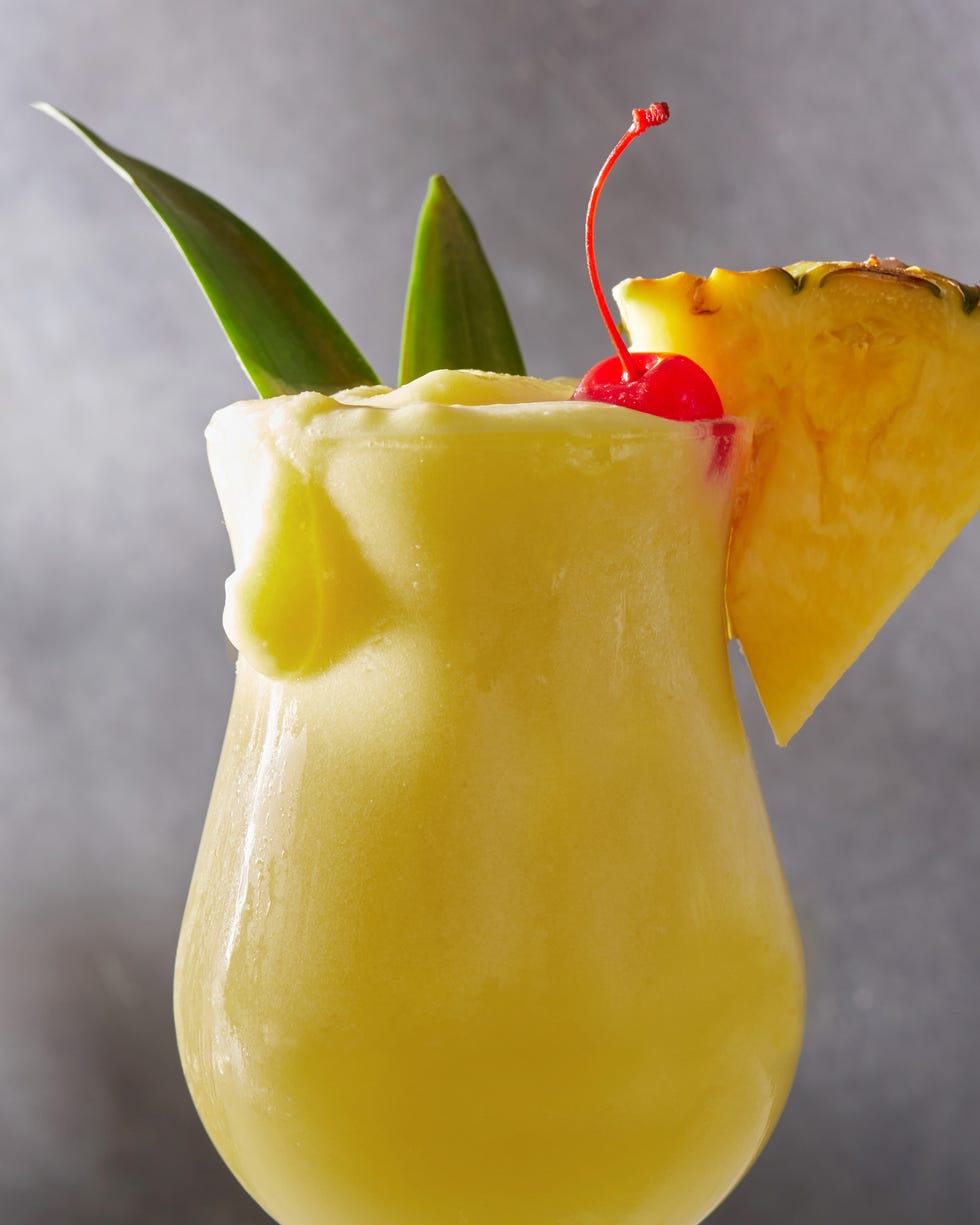 frozen pina colada cocktail with dark rum garnished with a maraschino cherry and pineapple wedge