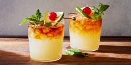 mai tai cocktail over crushed ice with a dark rum floater, maraschino cherry, lime, and mint garnish