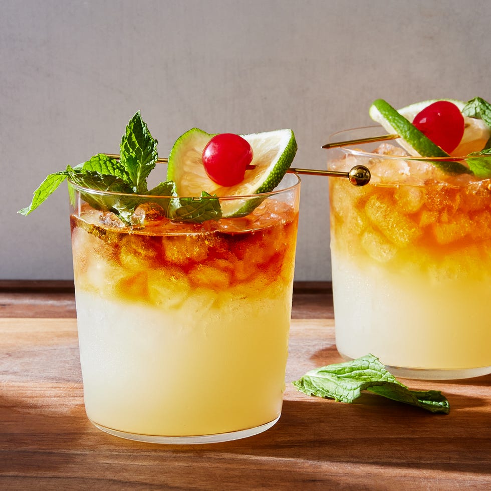 mai tai cocktail over crushed ice with a dark rum floater, maraschino cherry, lime, and mint garnish