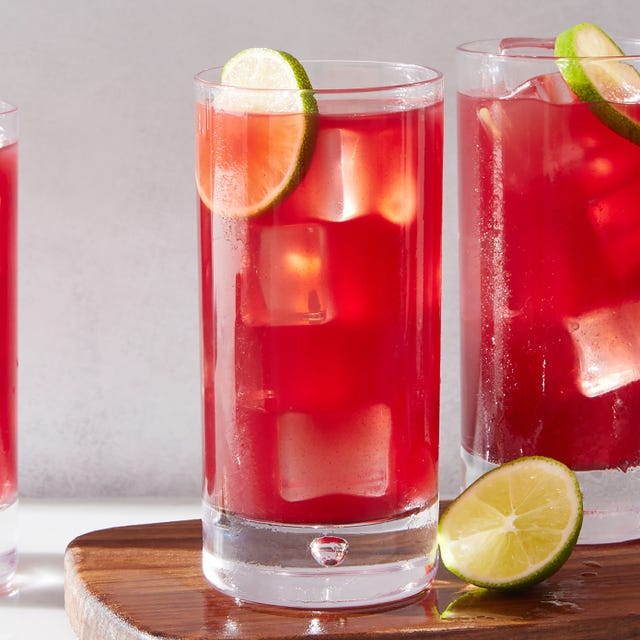 two glasses of bay breeze cocktail on a wooden cutting board with lime