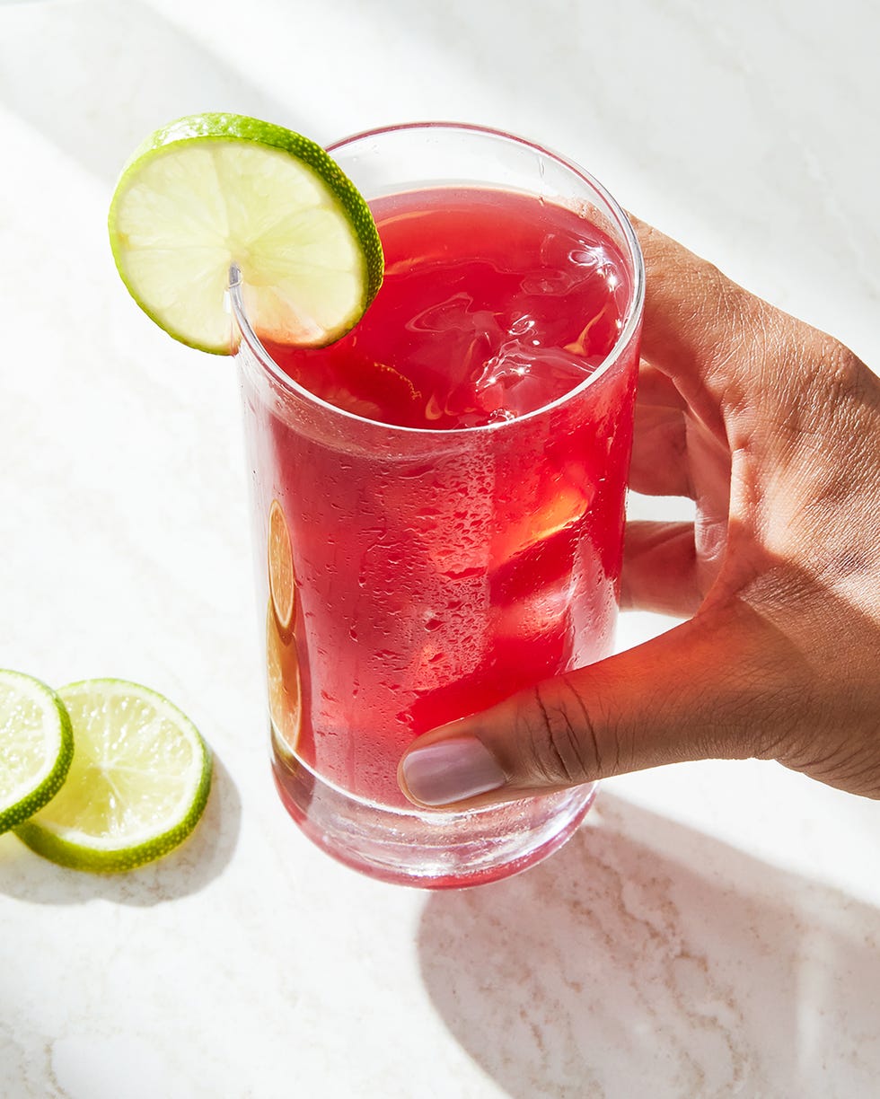 hand holding a bay breeze cocktail garnished with lime wheel