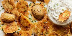 crispy parmesan potatoes on a baking sheet with a bowl of sour cream and chive dip