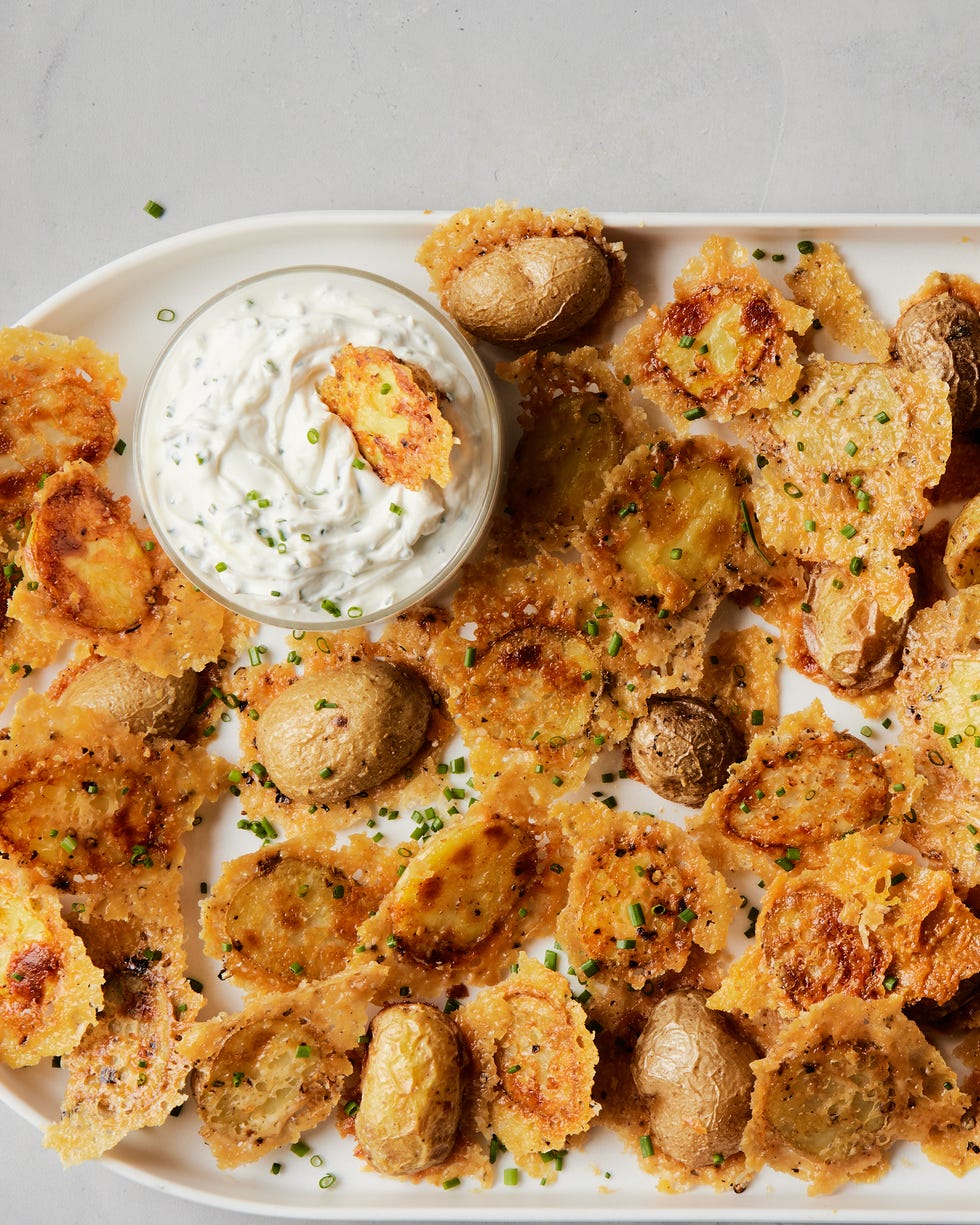 Crispy parmesan potatoes on a plate with a dollop of sour cream and chive sauce