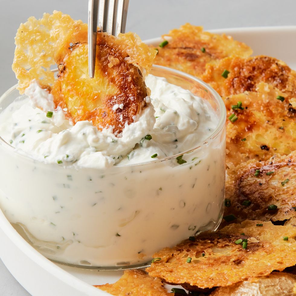 crispy parmesan potato being dipped into a bowl of sour cream and chive dip
