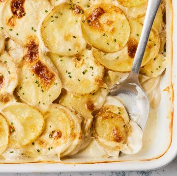 scalloped potatoes in a white baking dish with a silver serving spoon